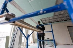 Drywall Installers. Men holding a gypsum board figured cut